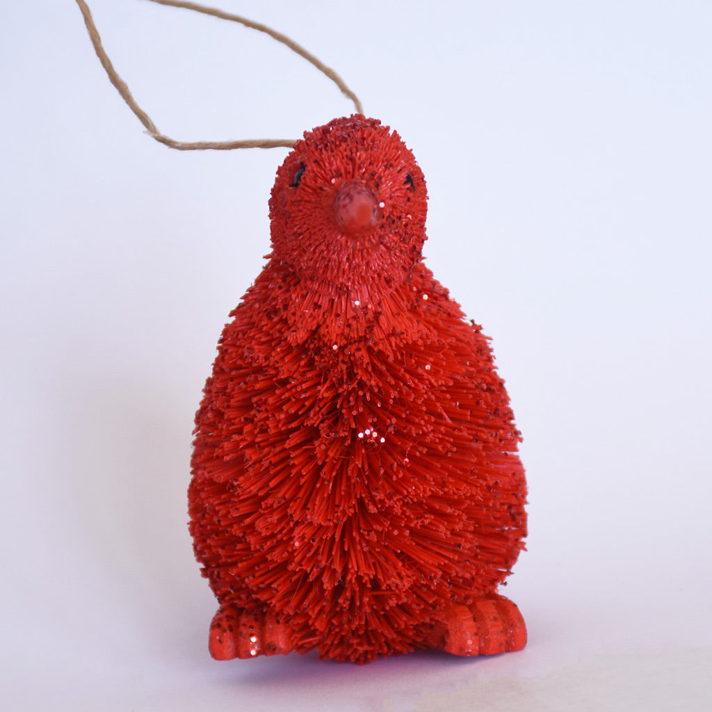 Decorative Bristle Kiwi bird ornament with glittery red finish on a white background