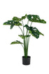 Artificial monstera plant in a black pot on a white background